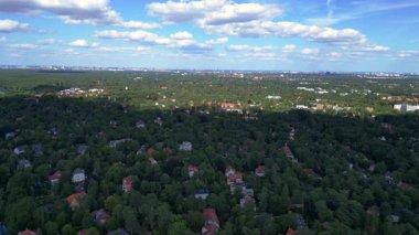 Hayır, Berlin 'de bir yerleşim bölgesi. Yoğun bir ormanın içine yerleştirilmiş evler var. Ufukta şehrin ufku görünüyor. Dolly sol İHA 