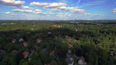 Hayır, Berlin 'de bir yerleşim bölgesi. Yoğun bir ormanın içine yerleştirilmiş evler var. Ufukta şehrin ufku görünüyor. doly sağ drone 