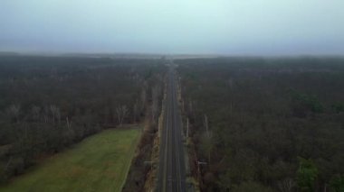 Demiryolu manzarası bulutlu gökyüzü altındaki büyük ormanı geçerek karamsar ve atmosferik manzaralar yaratıyor. Ters İHA uçuşu 