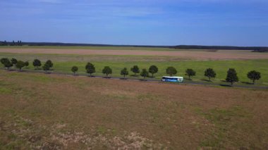 Kırsal bir yolda mavi gökyüzünün altındaki geniş tarlalardan geçen arabaların hava görüntüsü. geniş yörünge görünümü dronu 