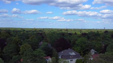 Hayır, Berlin 'de bir yerleşim bölgesi. Yoğun bir ormanın içine yerleştirilmiş evler var. Ufukta şehrin ufku görünüyor. uçuş üstü insansız hava aracı 