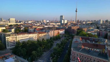 Berlin TV kulesi çatıların üstünde yükseliyor ve gün batımında Senefelderplatz 'da bir inşaat sahası var. panorama genel görünüm dronu 