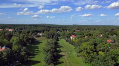 Schlachtensee gölleri, güneşli bir günde, masmavi gökyüzü ve bulutlarla çevrili yemyeşil ormanlarla çevrilidir. uçuş üstü insansız hava aracı 