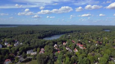 Schlachtensee gölleri, güneşli bir günde, masmavi gökyüzü ve bulutlarla çevrili yemyeşil ormanlarla çevrilidir. Ters İHA uçuşu 