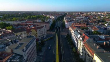 Berlin 'in yerleşim bölgesinden geçen sarı yükseltilmiş tren. Ters İHA uçuşu 