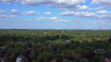 Hayır, Berlin 'de bir yerleşim bölgesi. Yoğun bir ormanın içine yerleştirilmiş evler var. Ufukta şehrin ufku görünüyor. İHA yükseliyor 