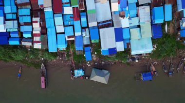 Güneydoğu Asya 'da gelişmekte olan bir ülke olan Kamboçya' daki Mekong nehri boyunca renkli kulübeleri olan bir balıkçı köyünün hava manzarası. dikey kuş bakışı dron 