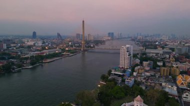 Rama VIII Köprüsü 'nün ve Chao Phraya Nehri' nin hava manzarası. Alacakaranlıkta Bangkok 'un aydınlatılmış şehir manzarası. statik üç ayaklı insansız hava aracı 