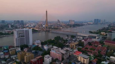 Rama VIII Köprüsü 'nün ve Chao Phraya Nehri' nin hava manzarası. Alacakaranlıkta Bangkok 'un aydınlatılmış şehir manzarası. Ters İHA uçuşu 