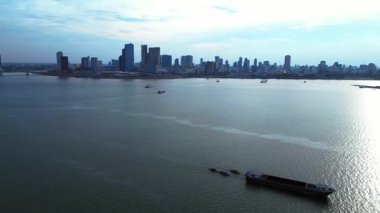 Kamboçya 'daki Phnom Penh ufuk çizgisi yakınlarındaki Mekong Nehri' nde kargo gemisi hareket ediyor. Yukarıdan insansız hava aracı görüntüleri 