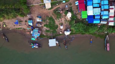 Güneydoğu Asya 'da gelişmekte olan bir ülke olan Kamboçya' daki Mekong nehri boyunca renkli kulübeleri olan bir balıkçı köyünün hava manzarası. Yukarıdan aşağıya doğru uçur 