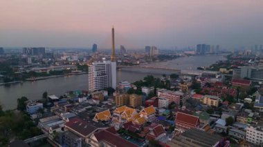 Rama VIII Köprüsü 'nün ve Chao Phraya Nehri' nin hava manzarası. Alacakaranlıkta Bangkok 'un aydınlatılmış şehir manzarası. panorama yörünge dronu 
