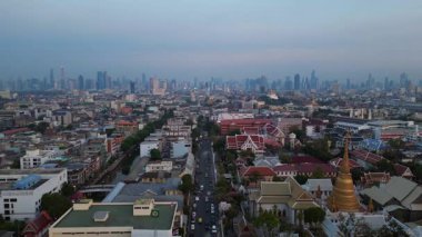 Geleneksel ve modern binaların arasında öne çıkan altın bir Chedi 'nin yer aldığı gün batımında Bangkok şehir manzarası. Yukarıdan insansız hava aracı görüntüleri 
