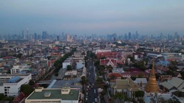 Geleneksel ve modern binaların arasında öne çıkan altın bir Chedi 'nin yer aldığı gün batımında Bangkok şehir manzarası. Dolly sol İHA 