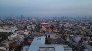 Geleneksel ve modern binaların arasında öne çıkan altın bir Chedi 'nin yer aldığı gün batımında Bangkok şehir manzarası. panorama genel görünüm dronu 
