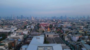 Geleneksel ve modern binaların arasında öne çıkan altın bir Chedi 'nin yer aldığı gün batımında Bangkok şehir manzarası. Yukarıdan insansız hava aracı görüntüleri 