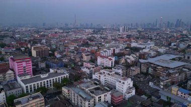 Bangkok üzerinde turuncu gün batımı çatıları ve binaları aydınlatıyor. Yukarıdan insansız hava aracı görüntüleri 