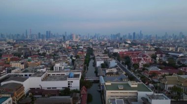 Geleneksel ve modern binaların arasında öne çıkan altın bir Chedi 'nin yer aldığı gün batımında Bangkok şehir manzarası. Ters İHA uçuşu 