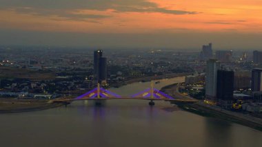 Phnom Penh 'in modern binaları, turuncu bulutlarla Mekong Nehri' nde günbatımını yansıtıyor. Yukarıdan insansız hava aracı görüntüleri 