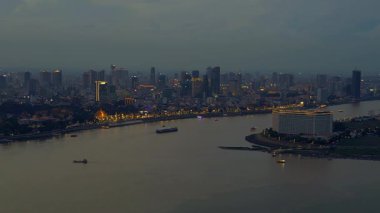 Phnom Penh 'in modern binaları, turuncu bulutlarla Mekong Nehri' nde günbatımını yansıtıyor. uçuş üstü insansız hava aracı 