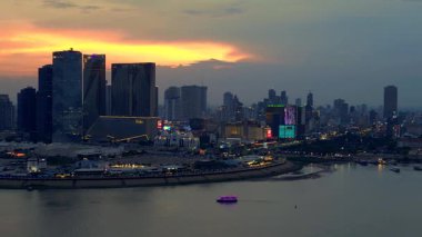 Phnom Penh 'in modern binaları, turuncu bulutlarla Mekong Nehri' nde günbatımını yansıtıyor. panorama genel görünüm dronu 