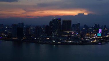 Phnom Penh 'in modern binaları, turuncu bulutlarla Mekong Nehri' nde günbatımını yansıtıyor. Ters İHA uçuşu 