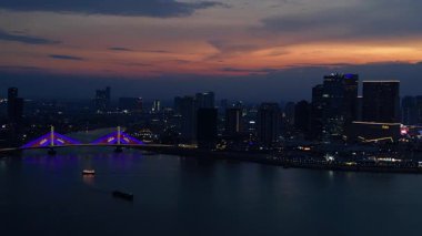 Phnom Penh 'in modern binaları, turuncu bulutlarla Mekong Nehri' nde günbatımını yansıtıyor. panorama genel görünüm dronu 
