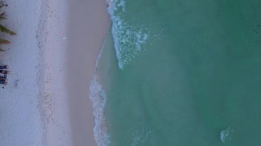 Turkuaz suyun havadan görünüşü Koh Rong adasının palmiye ağaçlarıyla beyaz kumsalları nazikçe yıkıyor. İHA kamerası aşağıya bakıyor 