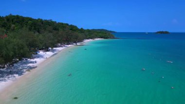 Kamboçya 'da tropik bir ada cenneti olan Koh Rong' un beyaz kumlu Kaoh Touch Sahili ve turkuaz sularının tadını çıkaran turistlerin hava manzarası. statik üç ayaklı insansız hava aracı 