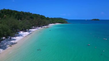 Kamboçya 'da tropik bir ada cenneti olan Koh Rong' un beyaz kumlu Kaoh Touch Sahili ve turkuaz sularının tadını çıkaran turistlerin hava manzarası. uçuş üstü insansız hava aracı 