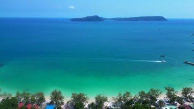 Kamboçya 'da tropik bir ada cenneti olan Koh Rong' un beyaz kumlu Kaoh Touch Sahili ve turkuaz sularının tadını çıkaran turistlerin hava manzarası. panorama genel görünüm dronu 