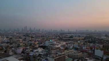 Bangkok üzerinde turuncu gün batımı çatıları ve binaları aydınlatıyor. Sağ drona döndür 