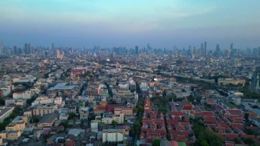 Puslu bir gündoğumunda çatıları ve gökdelenleri gösteren Bangkok kentsel hava manzarası. statik üç ayaklı insansız hava aracı 