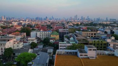 Puslu bir gündoğumunda çatıları ve gökdelenleri gösteren Bangkok kentsel hava manzarası. doly sağ drone 