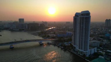 Chao Phraya Nehri, günbatımında, modern binalar ve Tayland 'da köprü ile denize açılan teknelerle. statik üç ayaklı insansız hava aracı 