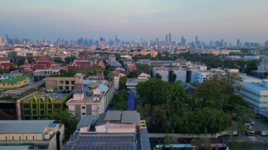 Puslu bir gündoğumunda çatıları ve gökdelenleri gösteren Bangkok kentsel hava manzarası. İHA yükseliyor 