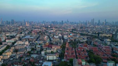 Puslu bir gündoğumunda çatıları ve gökdelenleri gösteren Bangkok kentsel hava manzarası. İHA alçalıyor 