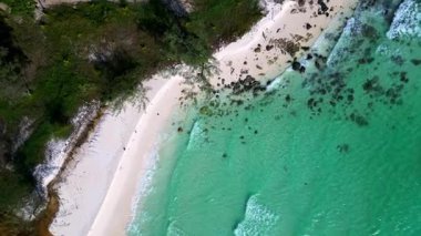 Turkuaz sudaki siyah taşlar açık mavi gökyüzüyle güneşli bir günde Kamboçya 'nın Koh Rong adasının beyaz kumsalını nazikçe yıkıyor. hız rampası hiper hareket zaman aşımı 