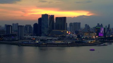 Phnom Penh ufuk çizgisi üzerinde gün batımı aydınlatılmış köprüyle birlikte tur botlarıyla Mekong Nehri 'ni geçiyor. panorama yörünge dronu 