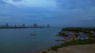Phnom Penh ufuk çizgisi üzerinde gün batımı aydınlatılmış köprüyle birlikte tur botlarıyla Mekong Nehri 'ni geçiyor. panorama genel görünüm dronu 