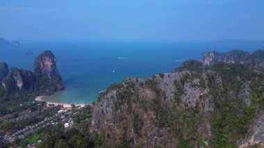 Tayland 'ın Krabi kentindeki Railay Sahili ve Phra Nang Mağara Sahili' nin hava manzarasında kireçtaşı kayalıklar, turkuaz su ve uzun kuyruklu botlar yer alıyor. uçuş üstü insansız hava aracı 