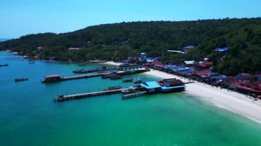 Kamboçya 'daki güzel koh rong adasının hava manzarasında turkuaz su, iskele, botlar ve tropikal ormanlar yer alıyor. panorama genel görünüm dronu 