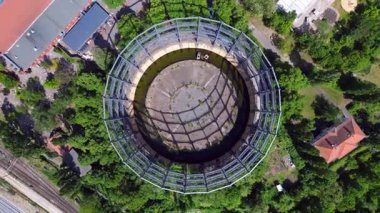 Berlin, Almanya 'da mavi bir gökyüzünün altında ağaçlar ve binalarla çevrili bir gaz sayacının hava görüntüsü. hız rampası hiper hareket zaman aşımı 