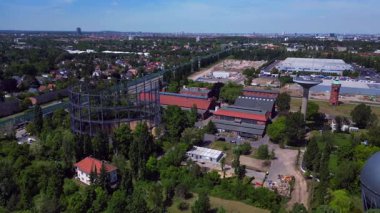 Berlin, Almanya 'da mavi bir gökyüzünün altında ağaçlar ve binalarla çevrili bir gaz sayacının hava görüntüsü. uçuş üstü insansız hava aracı 