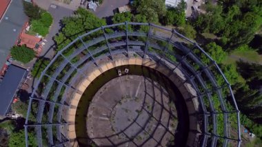 Berlin, Almanya 'da mavi bir gökyüzünün altında ağaçlar ve binalarla çevrili bir gaz sayacının hava görüntüsü. Drone 'u yukarı eğ 