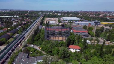 Berlin, Almanya 'da mavi bir gökyüzünün altında ağaçlar ve binalarla çevrili bir gaz sayacının hava görüntüsü. geniş yörünge görünümü dronu 
