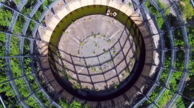 Berlin, Almanya 'da mavi bir gökyüzünün altında ağaçlar ve binalarla çevrili bir gaz sayacının hava görüntüsü. İHA kamerası aşağıya bakıyor 