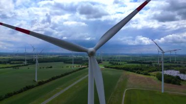 Rüzgar türbinleri Almanya 'da bulutlu bir gökyüzünün altında büyük bir rüzgar parkında temiz enerji üretiyor. Yaklaşın, yaklaşın, yaklaşın. 