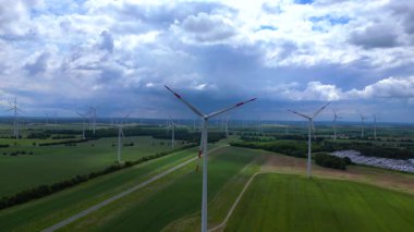 Rüzgar türbinleri Almanya 'da bulutlu bir gökyüzünün altında büyük bir rüzgar parkında temiz enerji üretiyor. İHA 'yı çek 