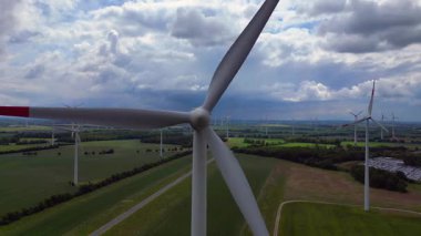 Rüzgar türbinleri Almanya 'da bulutlu bir gökyüzünün altında büyük bir rüzgar parkında temiz enerji üretiyor. Ters İHA uçuşu 